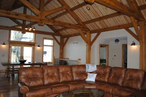 A living room with brown leather furniture and wood ceiling.